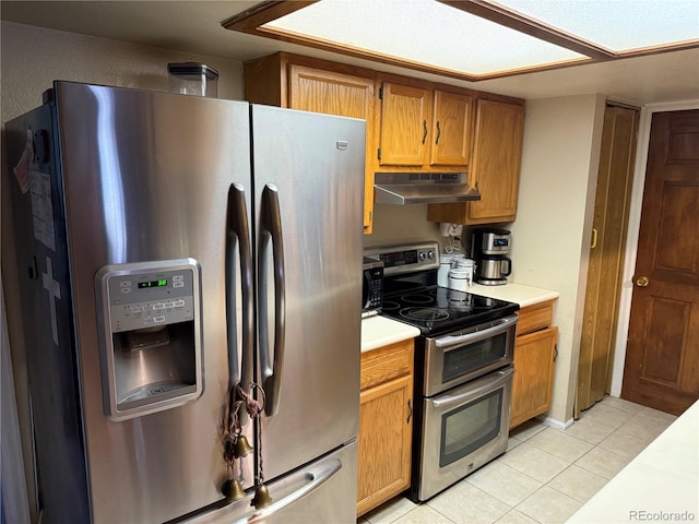 9410 W 89th Cir, Broomfield, CO 80021 - kitchen with stainless steel appliances, under cabinet range hood, light countertops, light tile patterned floors, and brown cabinetry