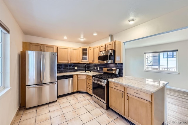 951 Tennyson St, Denver, CO 80204 - kitchen with stainless steel appliances, light stone counters, light brown cabinetry, decorative backsplash, and glass insert cabinets