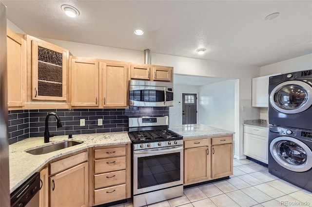951 Tennyson St, Denver, CO 80204 - kitchen with light brown cabinets, stacked washer / dryer, light tile patterned floors, a sink, and stainless steel appliances