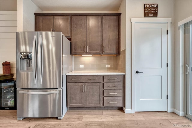 692 Sage Forest Ln, Monument, CO 80132 - kitchen featuring stainless steel fridge with ice dispenser, light wood-type flooring, dark brown cabinetry, and backsplash