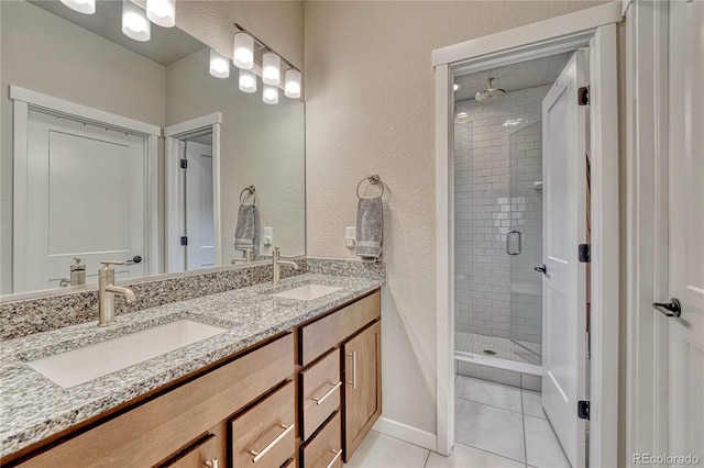 692 Sage Forest Ln, Monument, CO 80132 - bathroom with a shower stall, double vanity, tile patterned flooring, baseboards, and a textured wall