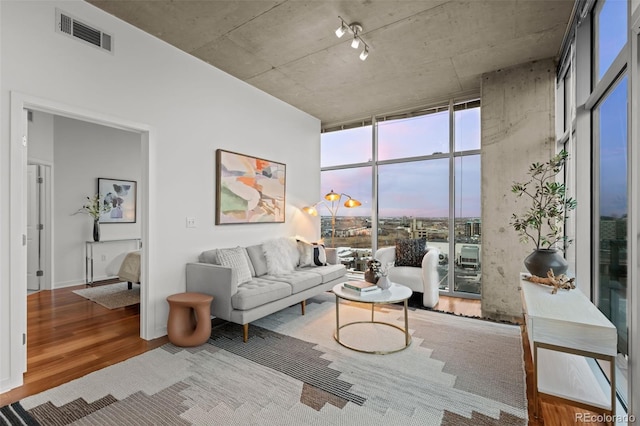 living room featuring floor to ceiling windows, wood finished floors, and visible vents