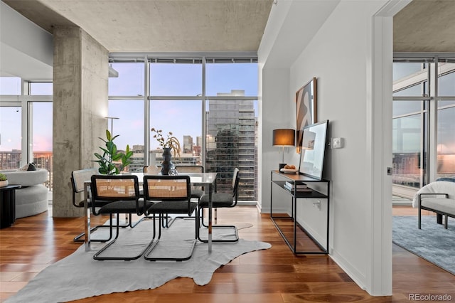 dining area featuring a wall of windows, baseboards, and wood finished floors