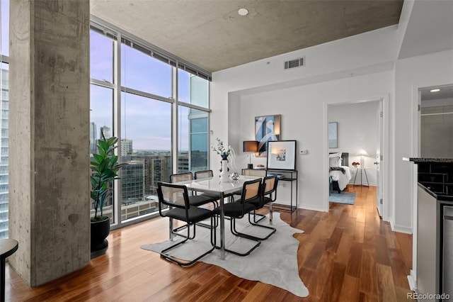 dining room with a wall of windows, wood finished floors, visible vents, and baseboards