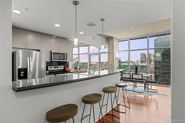 kitchen with visible vents, a view of city, a breakfast bar, appliances with stainless steel finishes, and light wood finished floors