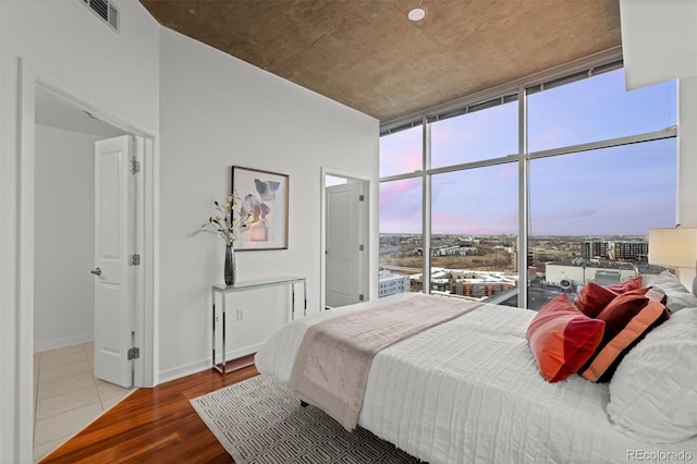 bedroom featuring visible vents, wood finished floors, baseboards, and expansive windows