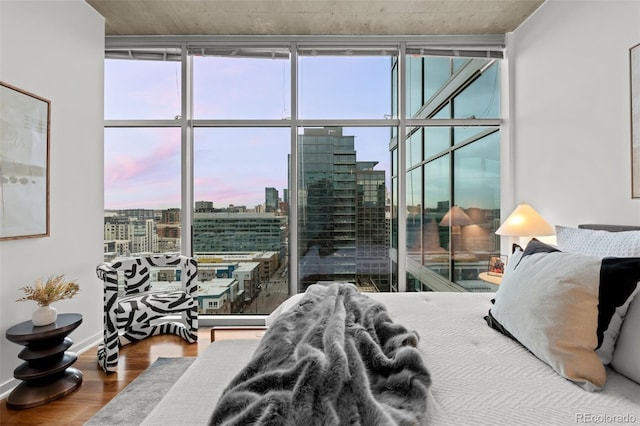 bedroom featuring a city view, a wall of windows, and wood finished floors