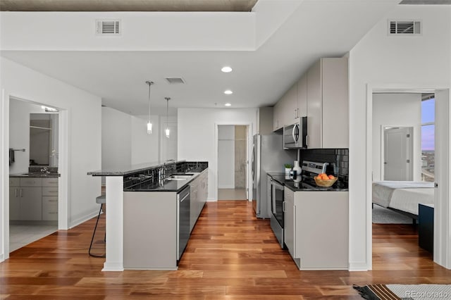 kitchen with dark countertops, visible vents, a breakfast bar, stainless steel appliances, and a sink