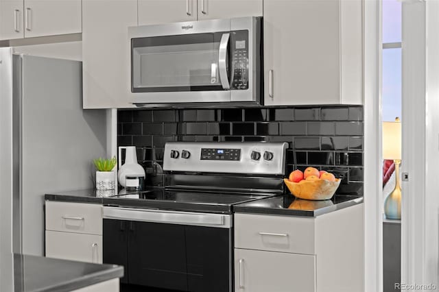 kitchen featuring stainless steel appliances, dark countertops, and white cabinetry