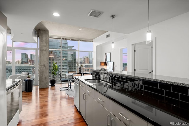 kitchen featuring a view of city, a sink, expansive windows, appliances with stainless steel finishes, and light wood finished floors