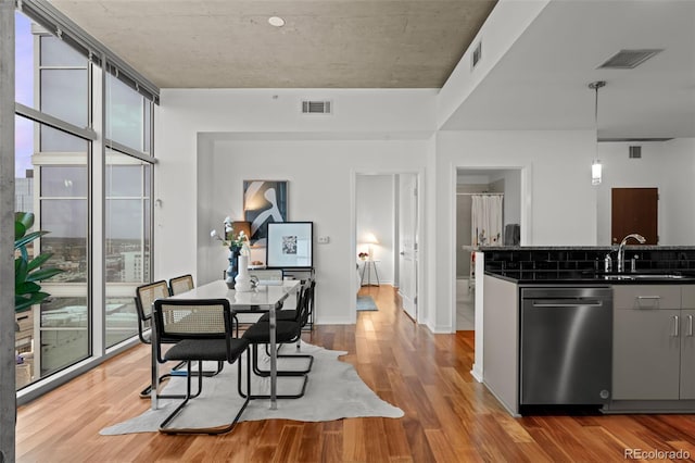 dining area with a wall of windows, visible vents, and light wood-type flooring