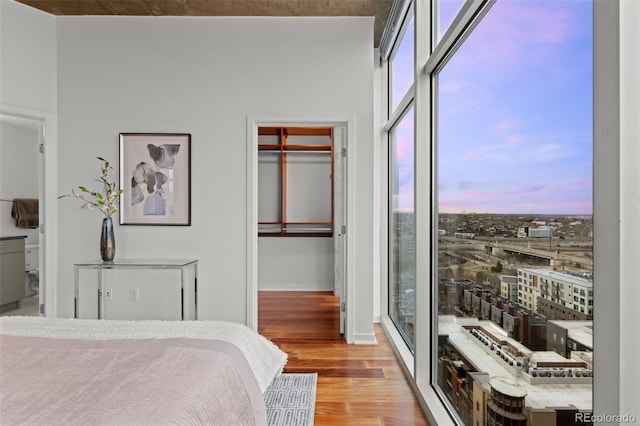 bedroom with wood finished floors, baseboards, and expansive windows