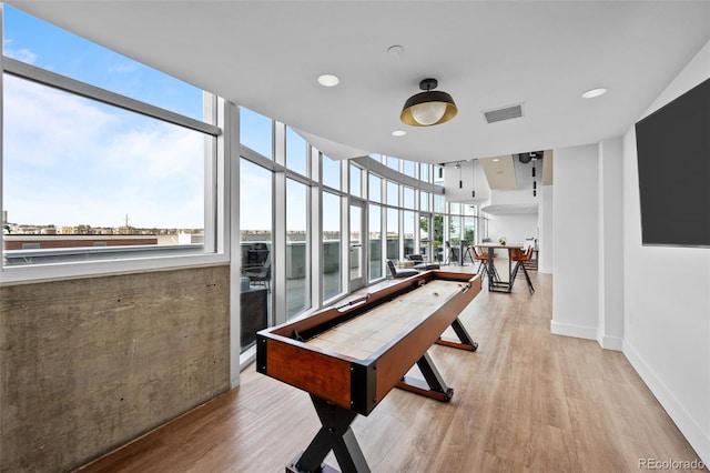 rec room with visible vents, recessed lighting, light wood-style floors, a wall of windows, and baseboards