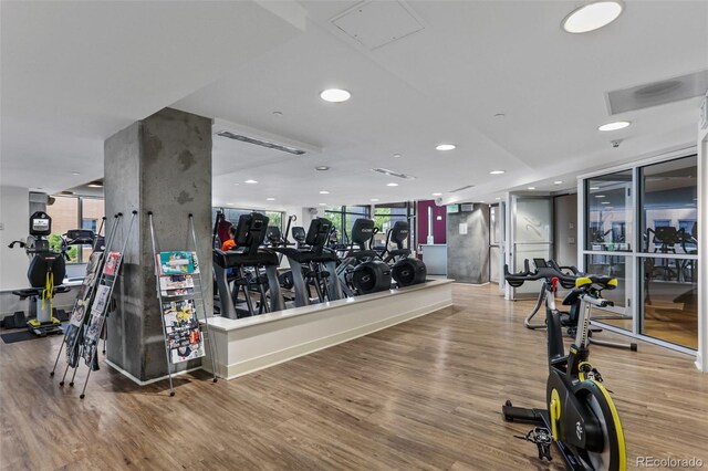 gym with a wall of windows, recessed lighting, and wood finished floors