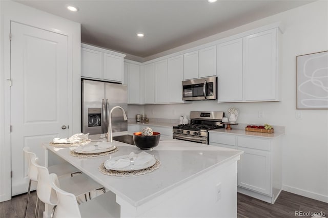 kitchen featuring white cabinetry, stainless steel appliances, and a kitchen island with sink