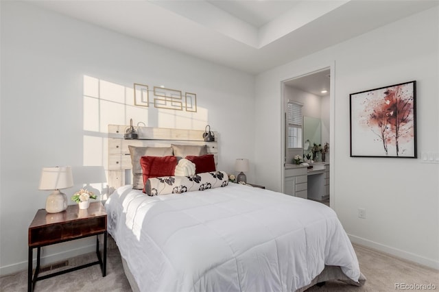 bedroom featuring connected bathroom and light colored carpet