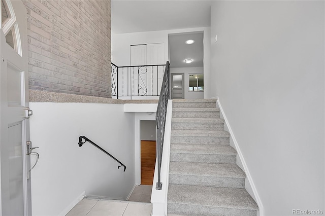 stairway with baseboards, a high ceiling, and tile patterned flooring