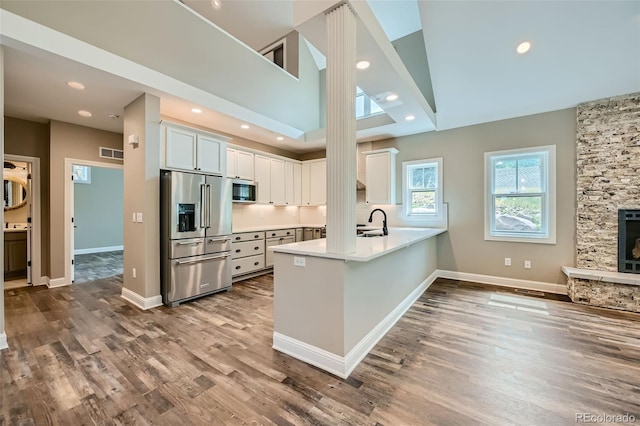 kitchen featuring a fireplace, white cabinetry, wood-type flooring, kitchen peninsula, and appliances with stainless steel finishes