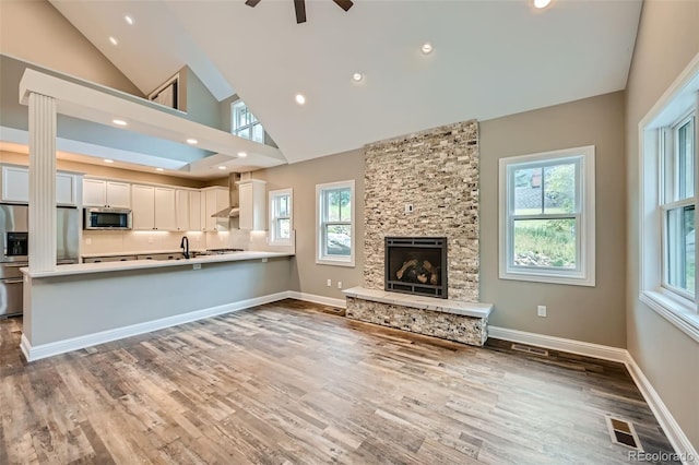 unfurnished living room featuring a healthy amount of sunlight, ceiling fan, and a fireplace