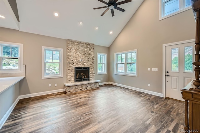 unfurnished living room with high vaulted ceiling, ceiling fan, a wealth of natural light, and a fireplace