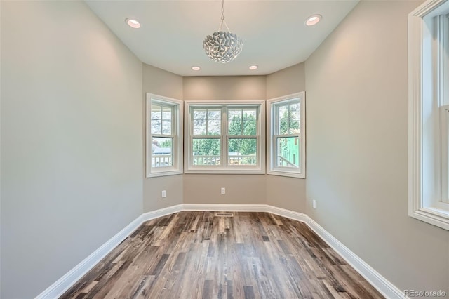 empty room featuring dark wood-type flooring and a notable chandelier