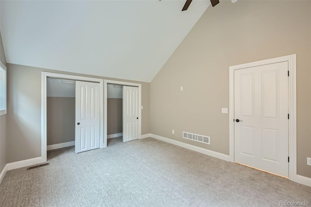 unfurnished bedroom with high vaulted ceiling, two closets, ceiling fan, and carpet floors