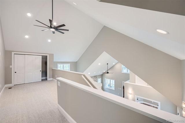 corridor featuring high vaulted ceiling and light colored carpet