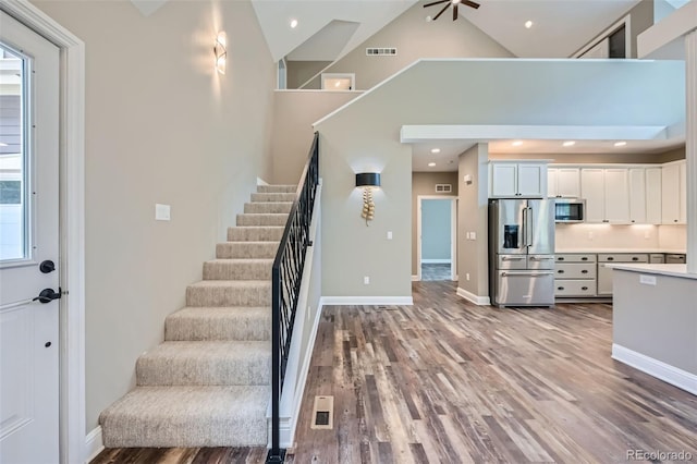 kitchen with high vaulted ceiling, a healthy amount of sunlight, appliances with stainless steel finishes, and white cabinets