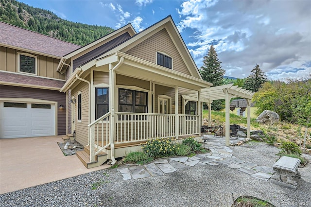 view of front of property with a garage, covered porch, a mountain view, and a pergola