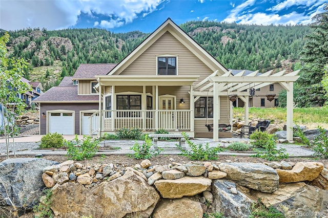 view of front of house featuring covered porch, a pergola, and a garage