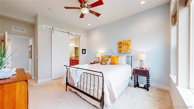 bedroom featuring a barn door, light colored carpet, visible vents, and baseboards