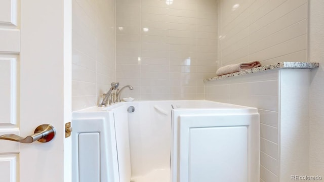 bathroom featuring a garden tub and tile walls