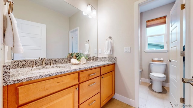 bathroom with toilet, a sink, tile patterned flooring, double vanity, and baseboards