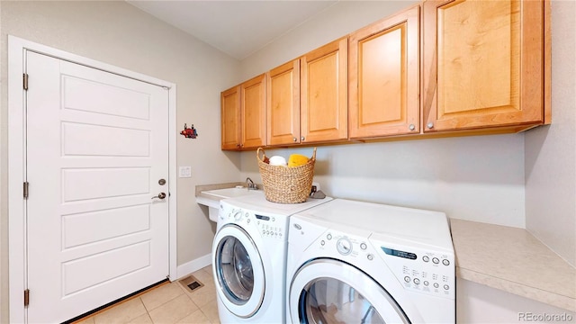 laundry room with light tile patterned floors, visible vents, cabinet space, a sink, and washing machine and dryer