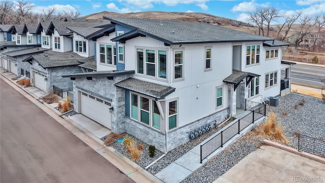 exterior space with concrete driveway, cooling unit, a residential view, and a shingled roof