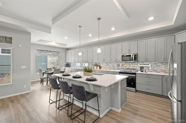 5108 N Quatar St, Aurora, CO 80019 - kitchen with a tray ceiling, decorative backsplash, stainless steel appliances, and light wood-style floors
