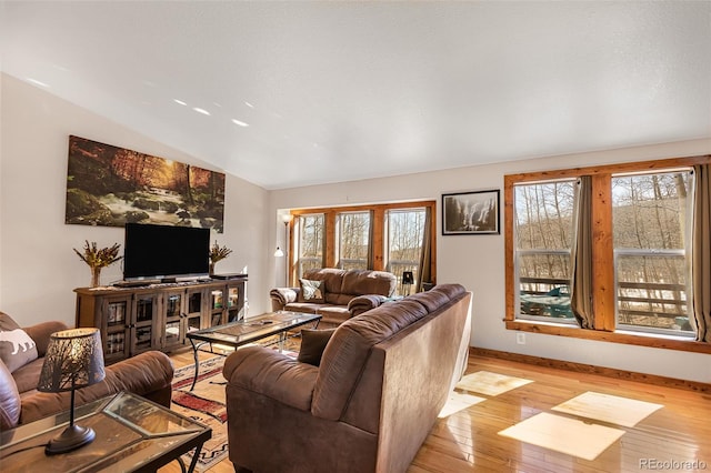 living room with light wood-type flooring, baseboards, and lofted ceiling