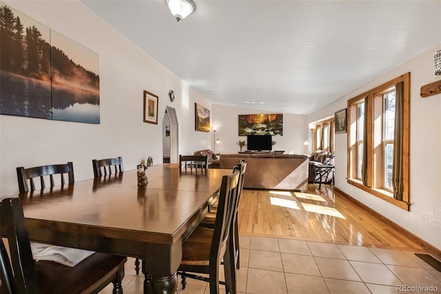 dining room featuring light tile patterned floors and arched walkways