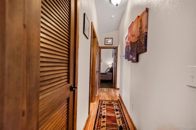 corridor featuring light wood-style flooring and baseboards