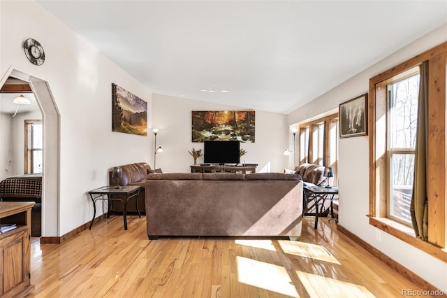 living area with lofted ceiling, light wood finished floors, and baseboards