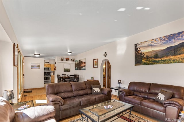 living room with arched walkways and light wood finished floors