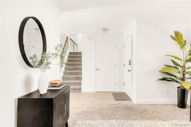 entryway featuring stairs, baseboards, wood finished floors, and crown molding