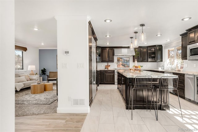 kitchen with visible vents, decorative backsplash, glass insert cabinets, appliances with stainless steel finishes, and a center island