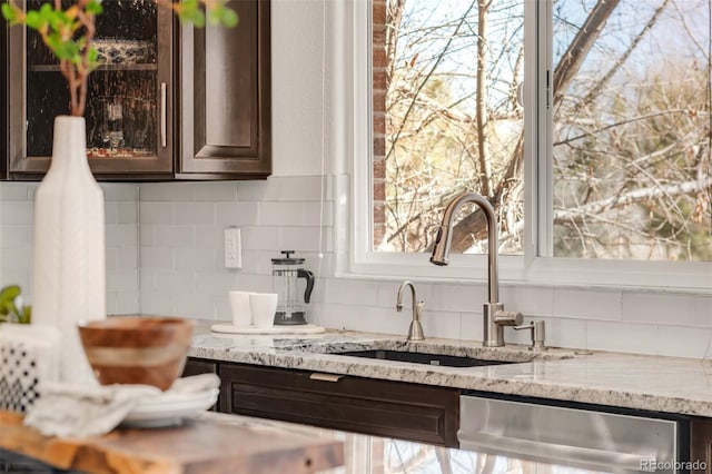 kitchen with dishwasher, dark brown cabinets, backsplash, and a sink