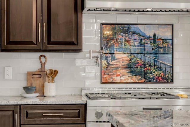 kitchen featuring light stone counters, tasteful backsplash, stove, and dark brown cabinetry