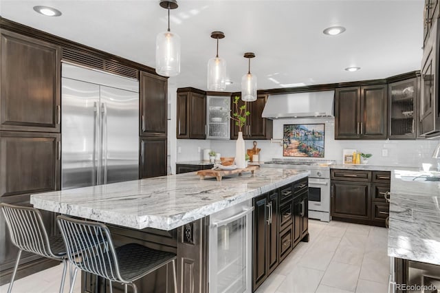 kitchen featuring wine cooler, wall chimney range hood, dark brown cabinets, and high quality appliances