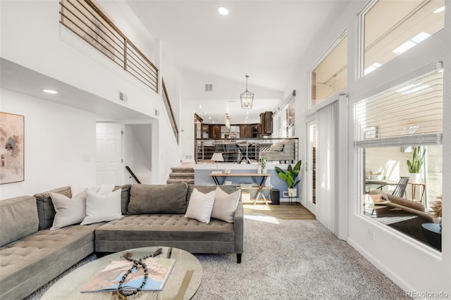 living area featuring recessed lighting, visible vents, light carpet, high vaulted ceiling, and stairs