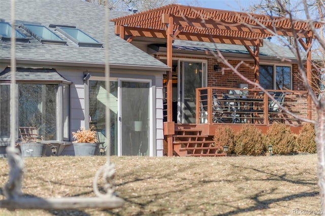 back of house with a shingled roof and a pergola