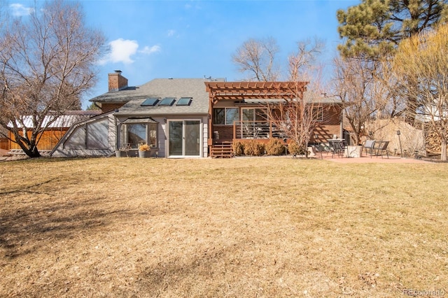 rear view of property with a chimney, a yard, a wooden deck, a patio area, and a pergola