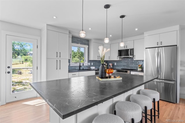 8836 Marathon Rd, Longmont, CO 80503 - kitchen with appliances with stainless steel finishes, a kitchen breakfast bar, light wood-type flooring, backsplash, and recessed lighting